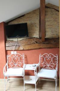 two white chairs sitting next to a table with a tv at Ma Longère Bressane in Chaveyriat