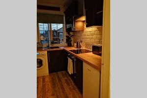a kitchen with black cabinets and a washer and dryer at Unique 2 Bedroom Apartment in the Ideal Location in Blackpool