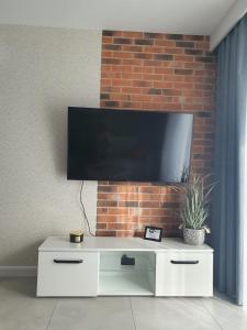 a flat screen tv on a brick wall at Clima Apartment II in Wrocław