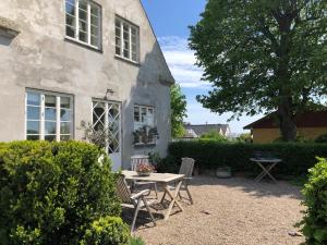 eine Terrasse mit einem Tisch und Stühlen vor einem Haus in der Unterkunft Det gamle badehotel i Grasten in Svendborg