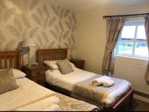 a bedroom with two beds and a window at The Jug & Glass Inn in Hartington
