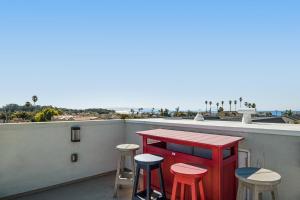 a table and stools on a balcony with a view of the beach at Coastal Perch in Pismo Beach