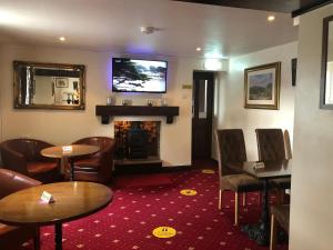 a bar with tables and chairs and a fireplace at The Jug & Glass Inn in Hartington
