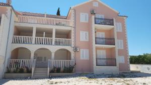 ein rosafarbenes Apartmentgebäude mit einem Balkon und einer Treppe in der Unterkunft Ruzica Apartments in Mirce