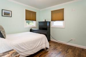 a bedroom with a bed and two windows at Luxury Cottage just 5 miles to downtown Asheville in Asheville