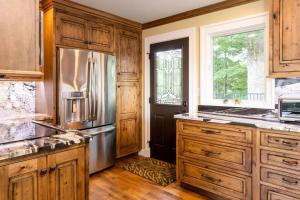 uma cozinha com armários de madeira e um frigorífico de aço inoxidável em Luxury Cottage just 5 miles to downtown Asheville em Asheville