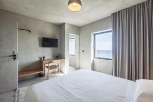 a hotel room with a bed and a desk and a window at CASA DA ILHA - Slow Living Residence & Suites in Ponta Delgada