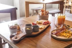 ポンタ・デルガダにあるCASA DA ILHA - Slow Living Residence & Suitesの木製テーブルの朝食用の食材のトレイ