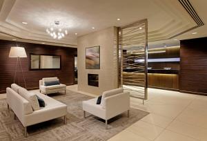 a lobby with two white chairs and a glass wall at Cambridge Suites Hotel Halifax in Halifax