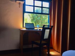 a desk with a laptop and a chair in front of a window at Flores de Cunha in Cunha