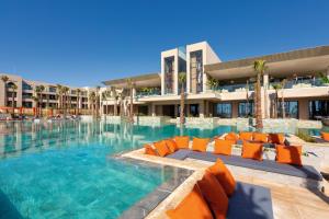 - une grande piscine avec des chaises orange dans un bâtiment dans l'établissement Hotel Riu Palace Tikida Taghazout - All Inclusive, à Taghazout