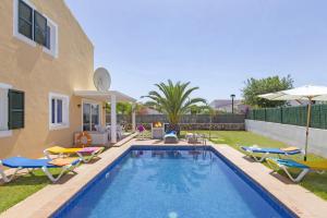 a swimming pool with chairs and a house at Villas Nura in Son Carrio