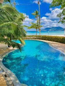 een blauw zwembad naast een strand met een palmboom bij Sea Pearl Beach Resort in Patong Beach