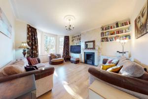 a living room with two couches and a fireplace at Superb 2 bedroom flat w garden - 1 min to Queen's Park in London
