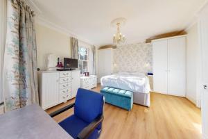 a bedroom with a bed and a blue chair at Superb 2 bedroom flat w garden - 1 min to Queen's Park in London