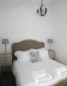 a bedroom with a white bed with a chandelier at Oswald House deluxe 2 bedroom apartment in Harrogate