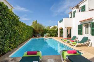 a swimming pool with lounge chairs and a house at Villa Menorca Juanita by Mauter Villas in Cala en Blanes