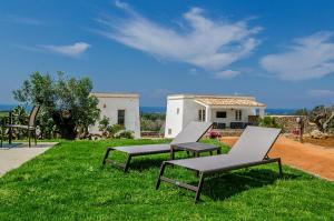 3 Stühle auf dem Gras vor einem Haus in der Unterkunft Villa Torre Dell'alto mare blocco n2 in Alliste