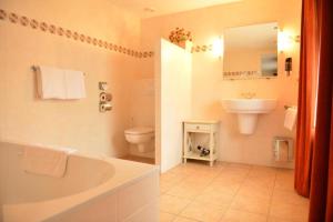 a bathroom with a tub and a toilet and a sink at Herberg de la Frontière in Slenaken