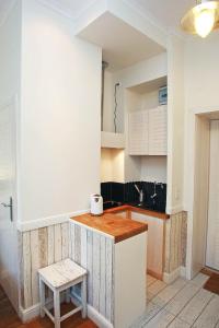 a kitchen with white cabinets and a stool at Grand Apartments - Anchor Apartament Sopot in Sopot