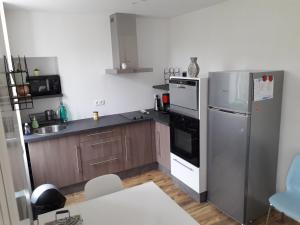 una cocina con nevera de acero inoxidable y armarios de madera en Agréable appartement à CAMBO LES BAINS, en Cambo-les-Bains
