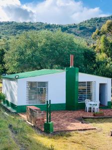 uma pequena casa verde e branca com uma mesa em Casa rural tipo loft em Guatavita