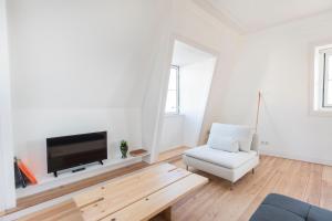 ein weißes Wohnzimmer mit einem TV und einem Stuhl in der Unterkunft Historical Apartment Santos IV in Lissabon