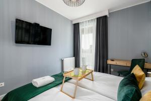 a bedroom with a bed with a table and a tv at Premium Apartments Poznań Airport by Renters in Poznań