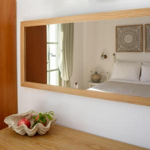 a mirror in a bedroom with a bowl of fruit on a table at Mirabeli Apartments & Suites in Pollonia
