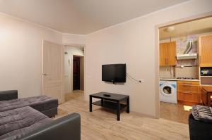 a living room with a couch and a tv at Omsk Sutki Apartments at 4th Poselkovaya 44 in Omsk