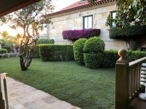 een tuin met struiken en een gebouw met een huis bij Hotel Playa Samil Vigo in Vigo