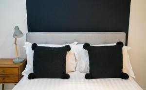 a bedroom with a bed with black and white pillows at Regent House deluxe 1 bedroom apartment in Harrogate
