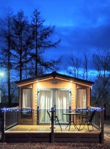 a small cabin with a table on a deck at night at The Wright Holiday Home in Forfar