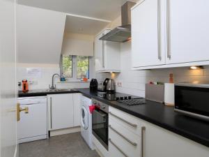uma cozinha com armários brancos e um balcão preto em 6 Chichester Court em Hope-Cove