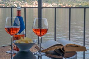 a table with two glasses of wine and an open book at Appartamento Comballo in Lezzeno