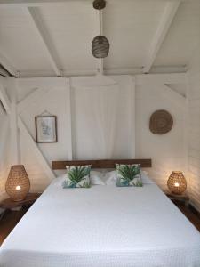 a bedroom with a white bed with two lamps at Kazalao in Prise dʼEau