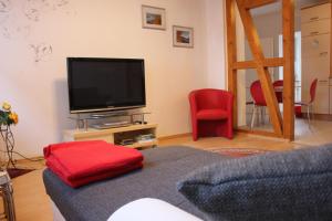 a living room with a television and red chairs at Ferienwohnung Rosemarie in Kamp-Bornhofen