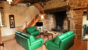 sala de estar con muebles verdes y chimenea de piedra en Le Petit Courtoux, en Saint-Germain-en-Coglès