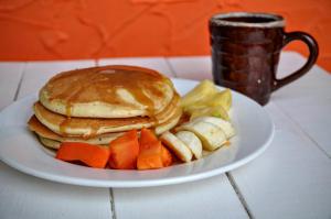 a plate of pancakes and vegetables and a cup of coffee at Bona Vida Hostel in Ríohacha