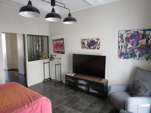 uma sala de estar com uma televisão de ecrã plano e um sofá em Appartement avec jardin privatif em Fréjus