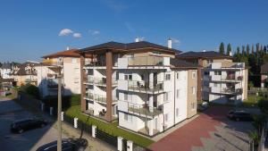 an apartment building with balconies and cars parked in a parking lot at Laguna Beach Apartmanok in Siófok