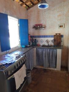 a kitchen with a stove and blue cabinets and a window at SITIO RUSTICO BEIRA RIO in Guararema