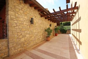 an external walkway with a stone wall and a wooden pergola at Appartamenti Borgo in Gardone Riviera