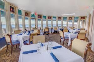 un restaurante con mesas y sillas blancas y el océano en Club Wyndham Bay Voyage Inn, en Jamestown