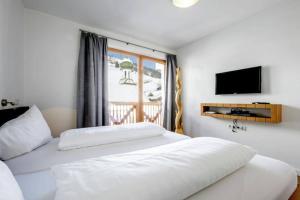 a bedroom with a white bed and a television at Lovely Spacious Apartment Gerlos -Owner- in Gerlos