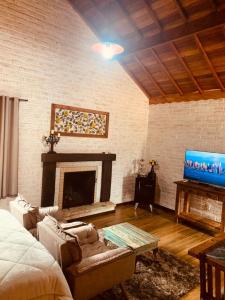 uma sala de estar com lareira e televisão em Chalé Villa Magrini em Monte Verde