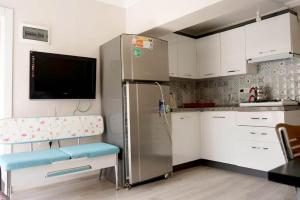 uma cozinha com um frigorífico de aço inoxidável e armários brancos em Ören Konak Apart Otel em Burhaniye