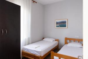 two beds in a room with white walls at Sarafos Apartment Stavros Rooms in Stavros