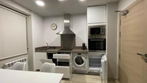 a kitchen with a washing machine and a microwave at Apartamentos Puertas del Orbigo in Carrizo de la Ribera