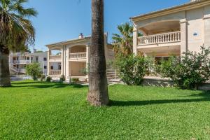 una gran casa con palmeras en el patio en Apartment Countess of the Bay Garden C, en Puerto de Alcudia